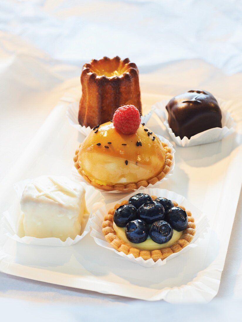 Petit fours, cannele, tartlets with lemon and mascarpone cream and blueberries, mini cheesecakes with raspberries