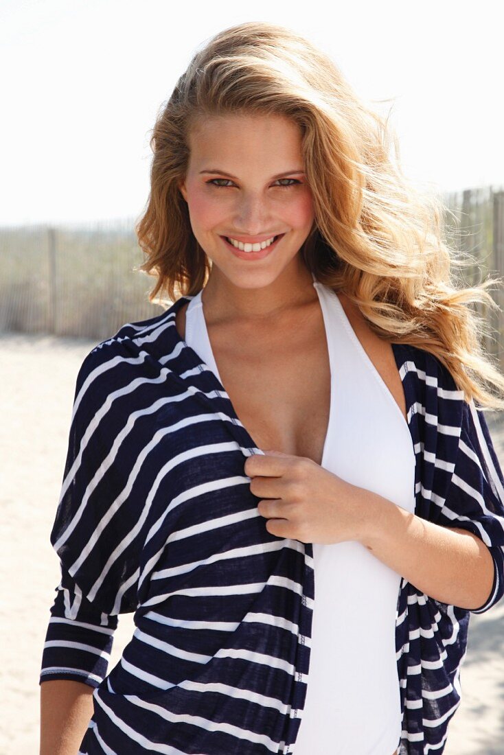 A young blonde woman wearing a blue-and-white stripped jacket over a swim suit