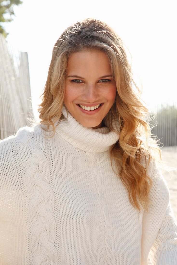 A young blonde woman wearing a white knitted roll-neck jumper