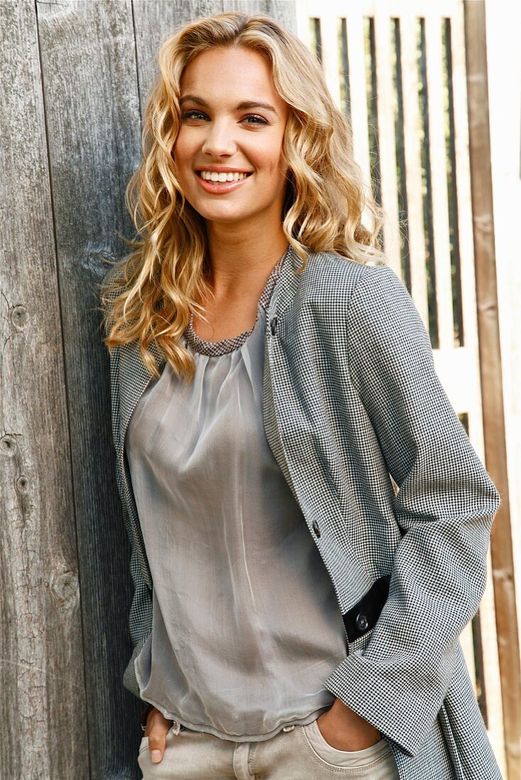 A young blonde woman wearing a grey blouse and a matching jacket