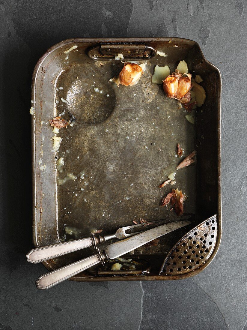Remains of food and carving cutlery in a roasting tin