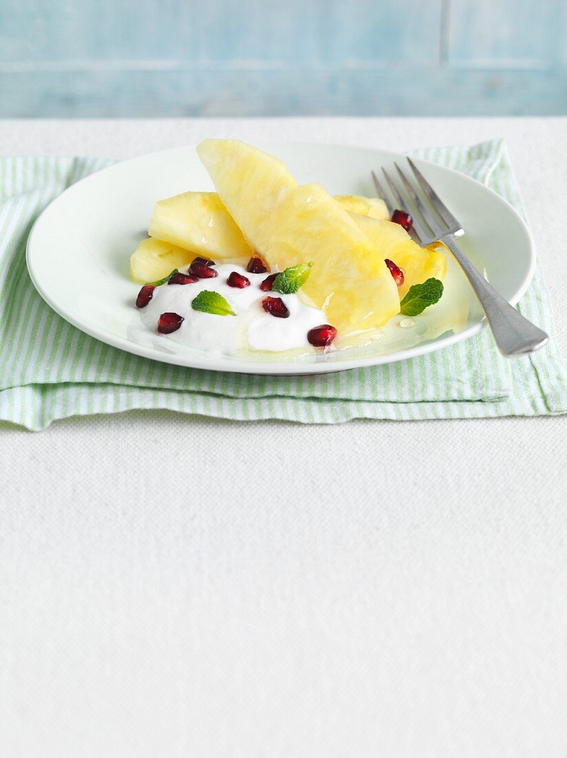 Ananasdessert mit Joghurt, Granatapfelkernen und Minzeblättchen