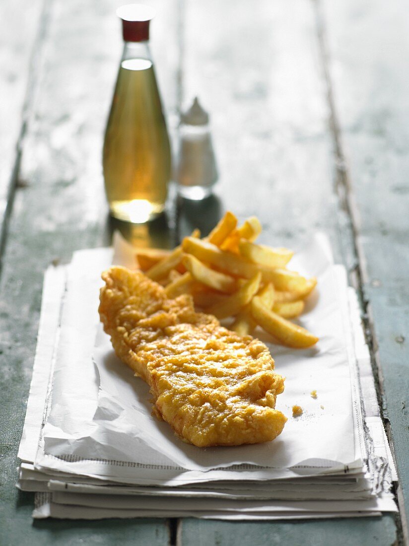 Fisch und Chips auf Zeitung mit Salz und Essig