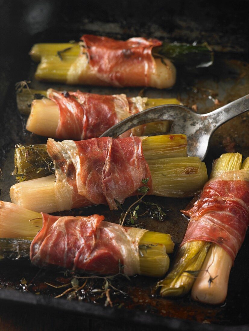 Leeks wrapped in Parma ham on a baking tray