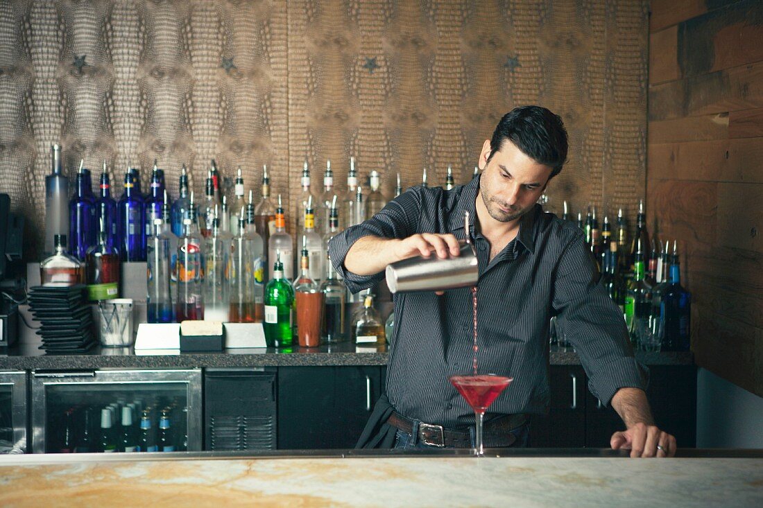 A bartender mixing cocktails at a bar