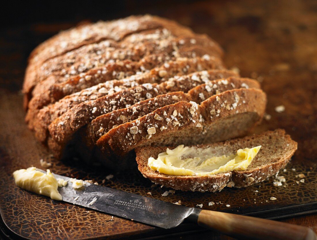 A loaf of soda bread, sliced, with one slice buttered