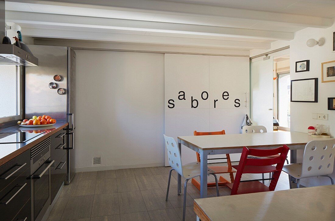 Moderne Wohnküche mit Essplatz; Einbauschrank mit spanischem Schriftzug auf raumhoher Schiebetür