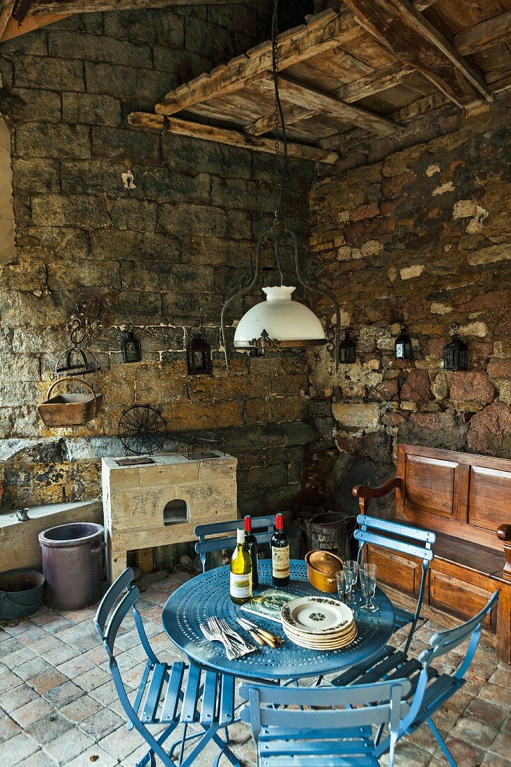 Himmelblau lackierter Bistrotisch mit Gartenstühlen und antiker, französischer Pendelleuchte in historischem Stallgebäude