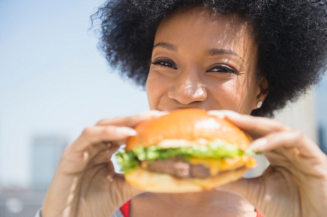 An African American woman eating a cheeseburger