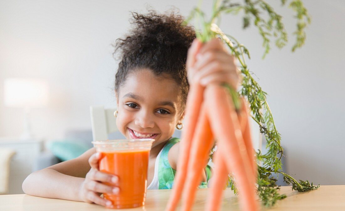 Afroamerikanisches Mädchen trinkt Karottensaft