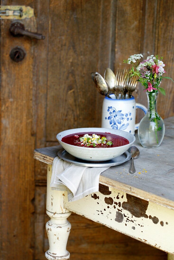 Beetroot soup with sheep's cheese gremolata on a rustic table