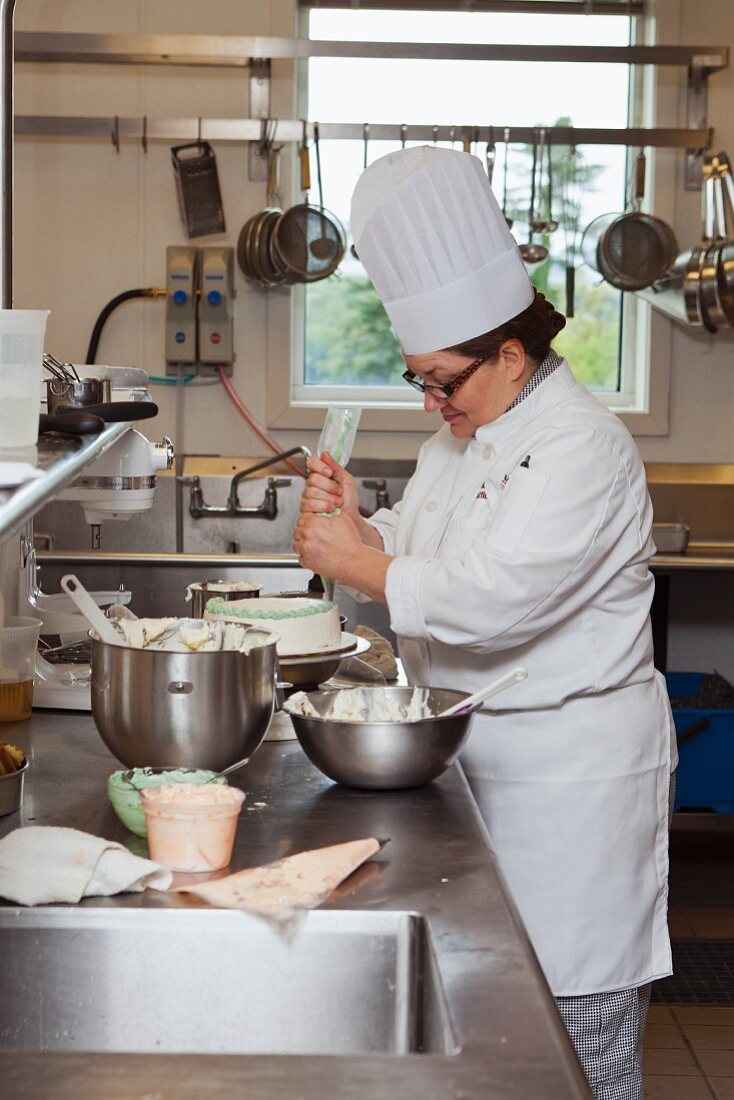 Köchin verziert Torte mit Zuckerguss