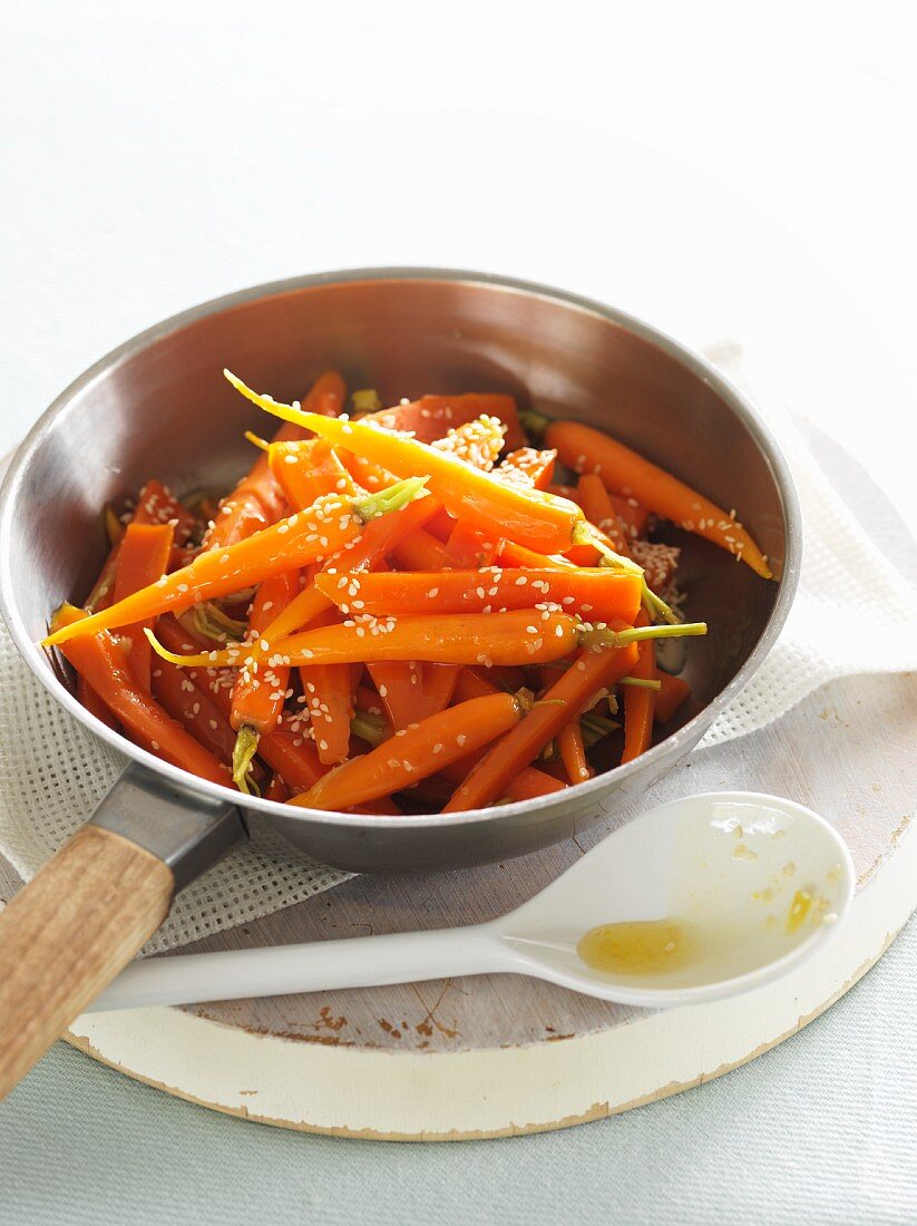 Baby carrots in pan with honey, ginger and sesame seeds