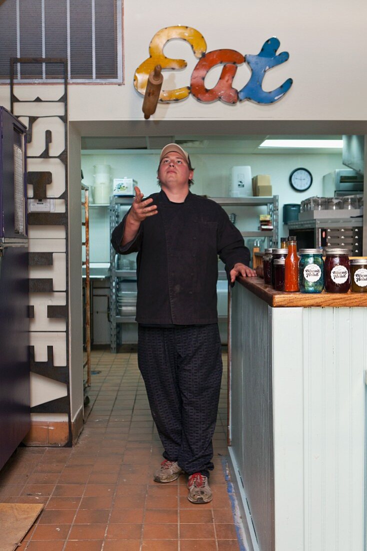 A chef in a restaurant throwing a rolling pin in the air