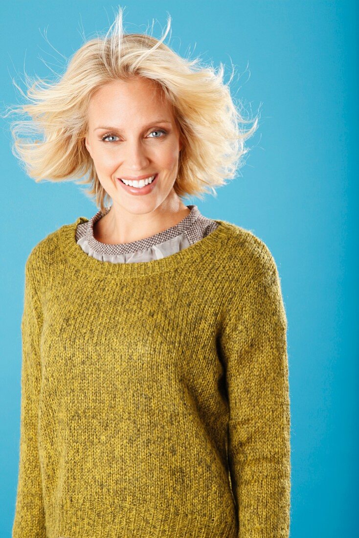 A young blonde woman wearing an olive green knitted jumper