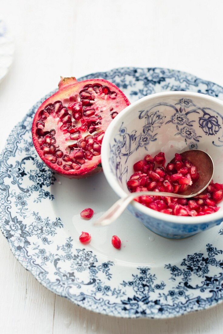 Half a pomegranate and pomegranate seeds in vintage plate