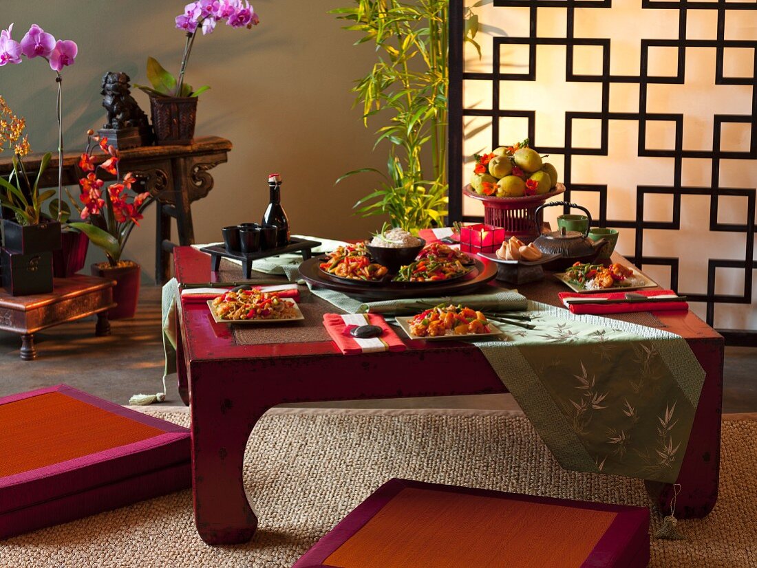 Gedeckter Tisch mit asiatischen Gerichten in asiatischem Ambiente