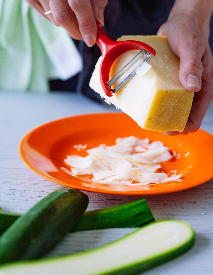 Parmesan being grated with a potato peeler