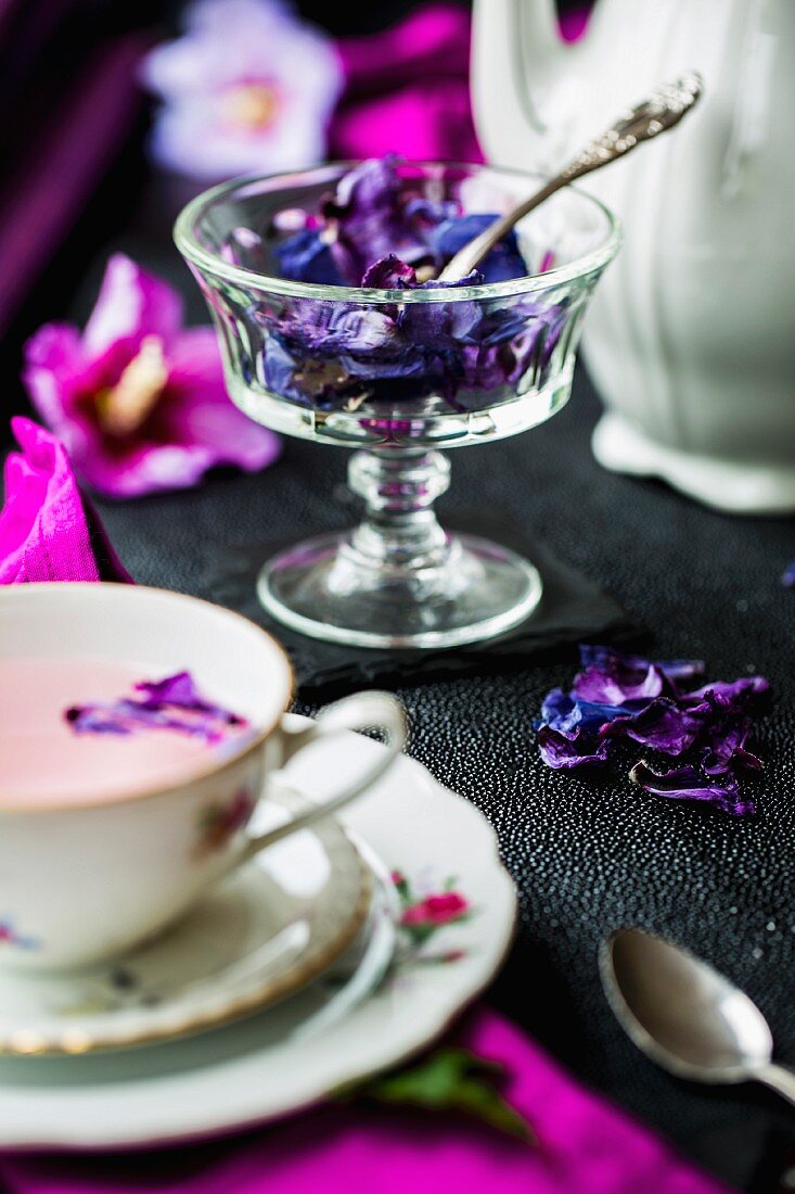 Dried hibiscus petals in a glass bowl, a teapot and a cup of hibiscus flower tea