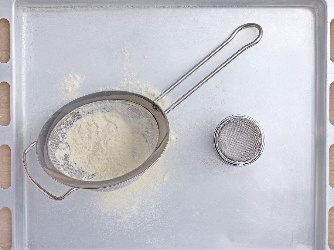 A sieve and a tin of icing sugar