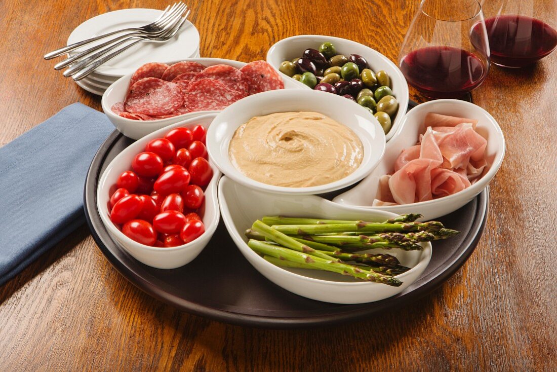 Hummus Dip mit Schinken, Salami, Oliven und Gemüse in Schälchen