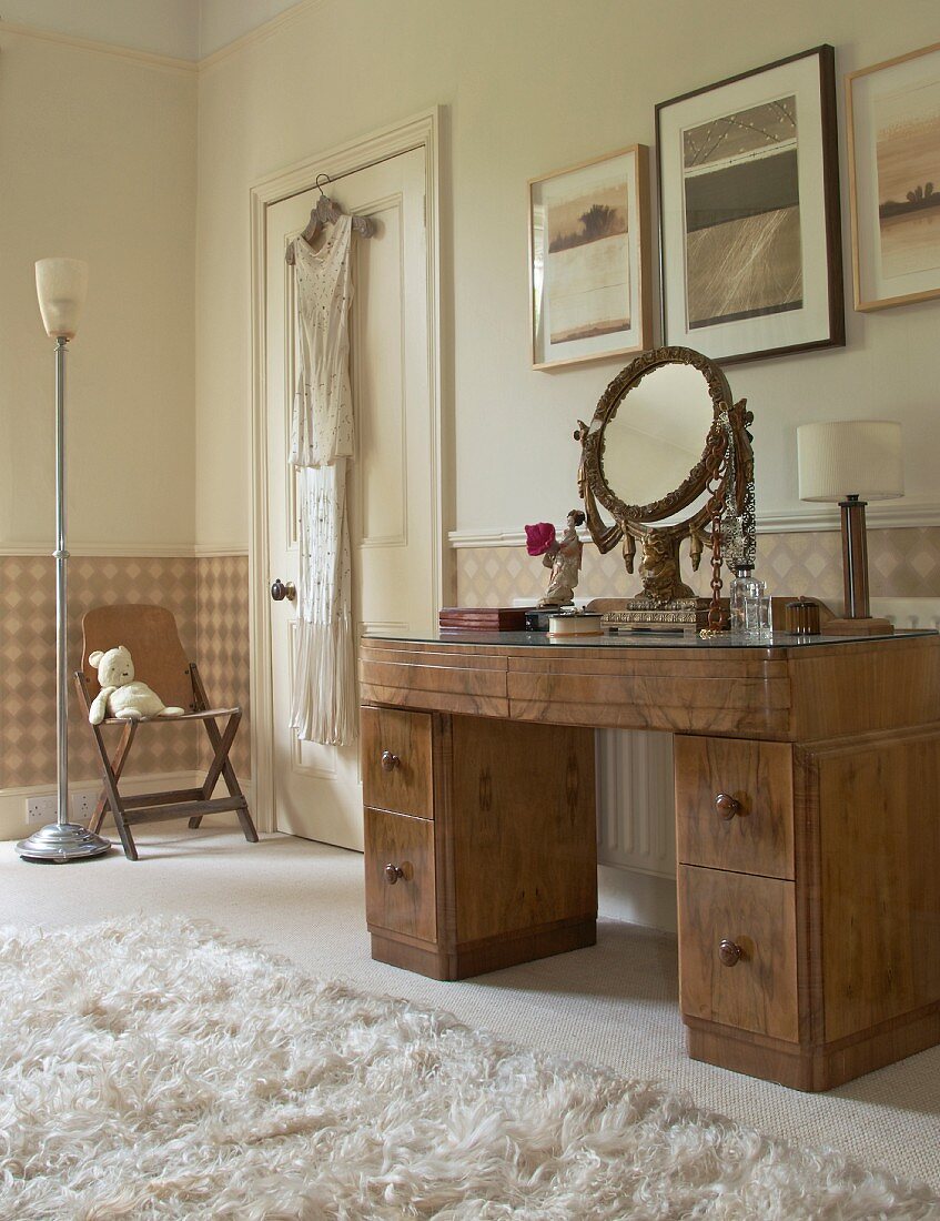 Bedroom in soft shades of beige and brown; pictures above antique, walnut dressing table with ornate brass mirror