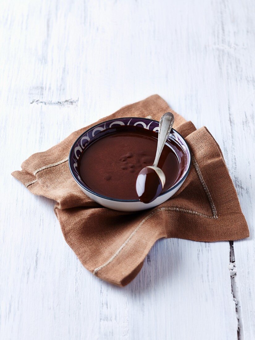 A bowl of melted chocolate and a spoon