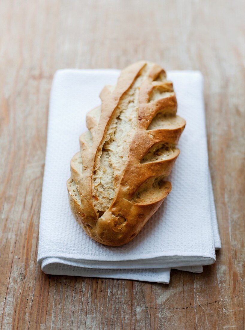 A rustic loaf of French bread on a tea towel