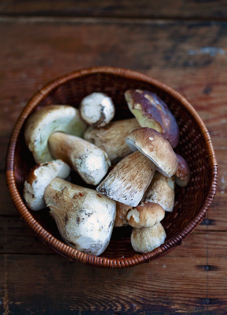 A basket of fresh porcini mushrooms on a wooden surface