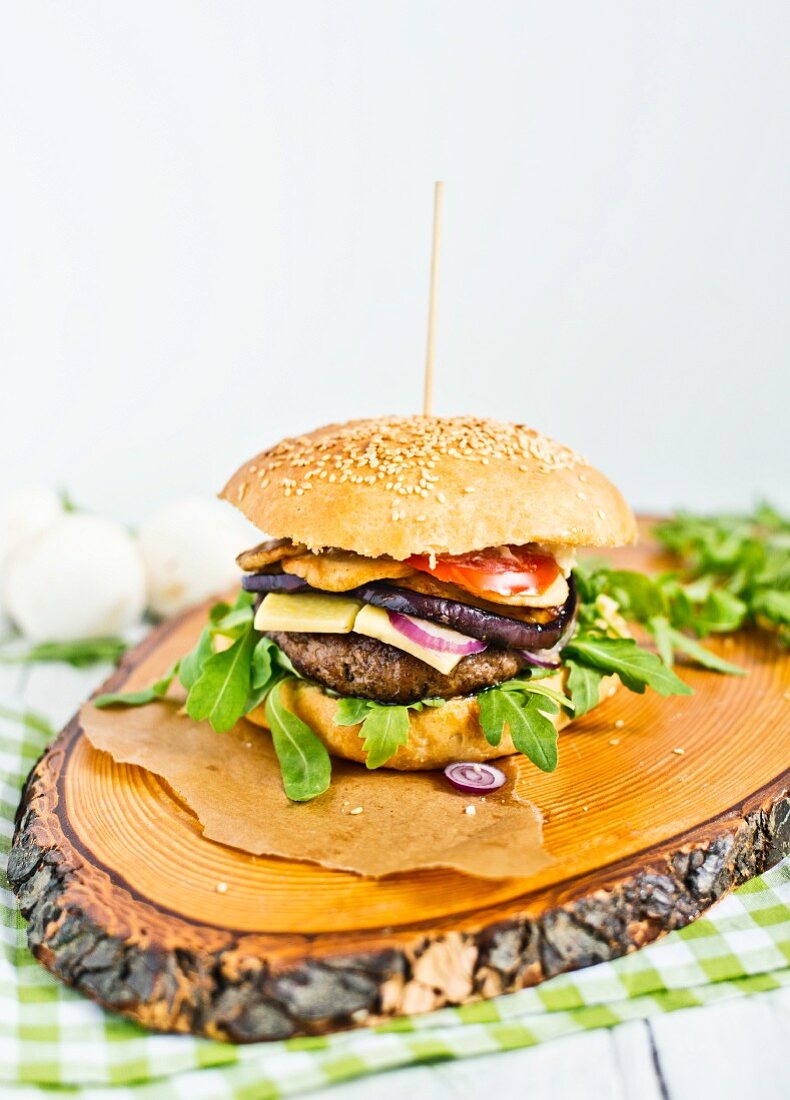 A cheeseburger with rocket on a wooden platter
