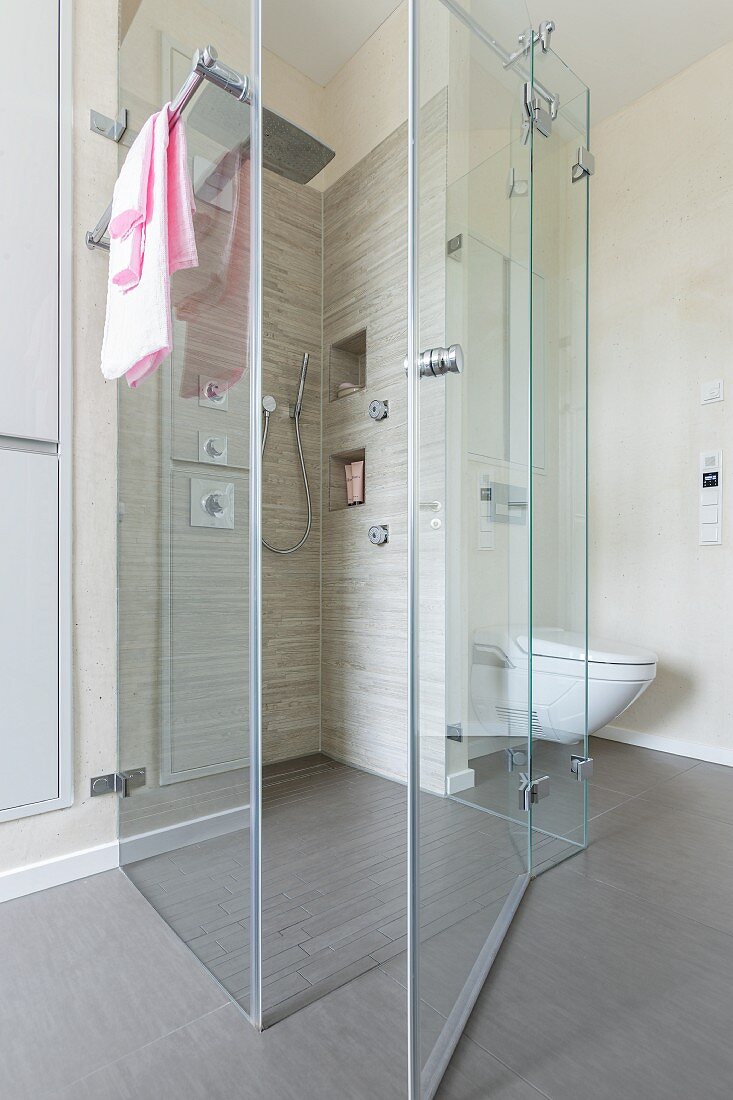 Bodenebener, gefliester Duschbereich mit Regendusche und Seitenbrausen, Glasabtrennung in Designerbad