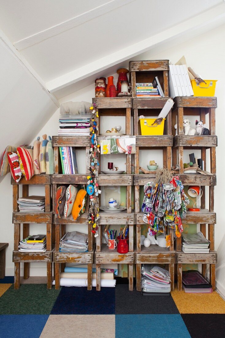 Vintage shelving made from stacked, old stools in child's bedroom; patchwork floor made from carpet tiles of different colours