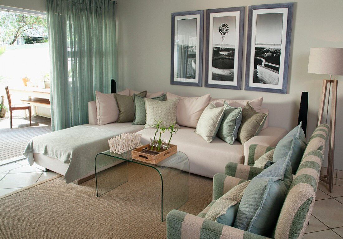 Lounge area with access to terrace - armchairs, chaise sofa, glass coffee table and framed pictures on wall