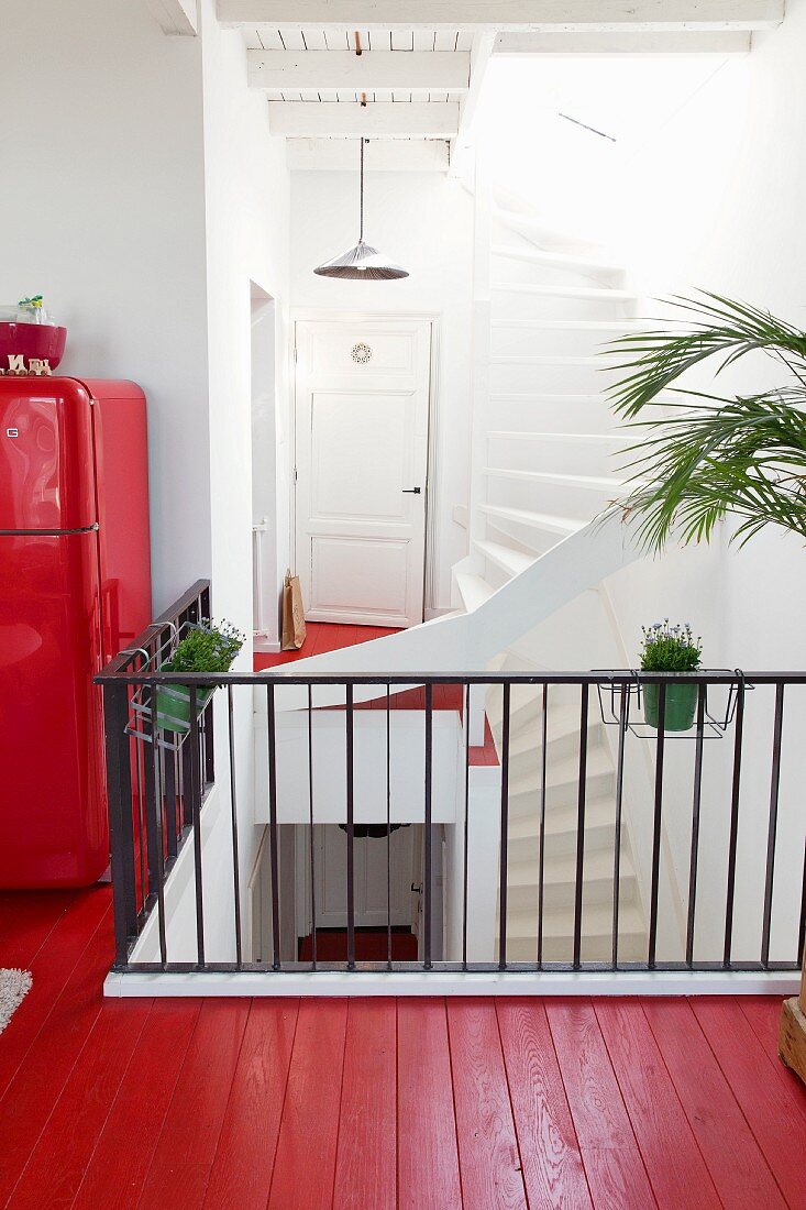 Red-painted wooden floor and black metal stair rail on gallery in open-plan stairwell