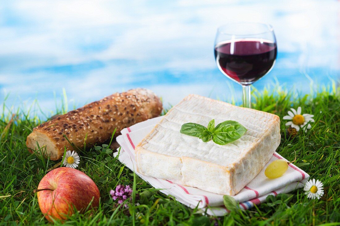 An arrangement of cheese featuring a glass of red wine and an apple