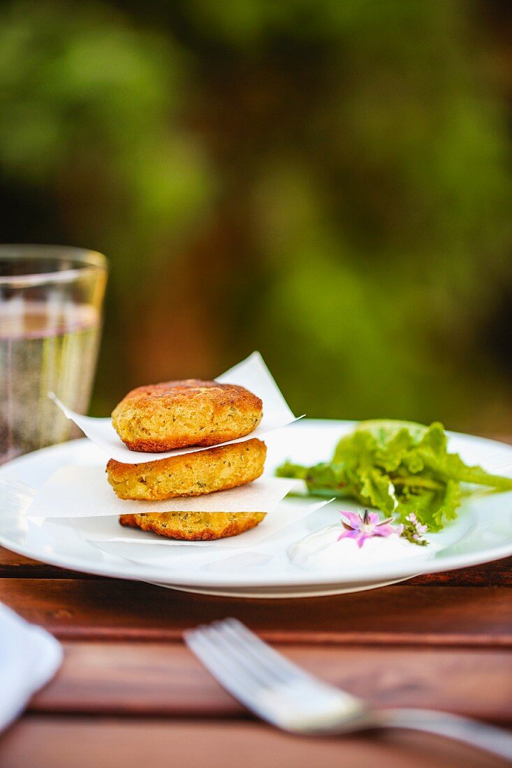 Salmon cakes with salad and borage flowers on a garden table