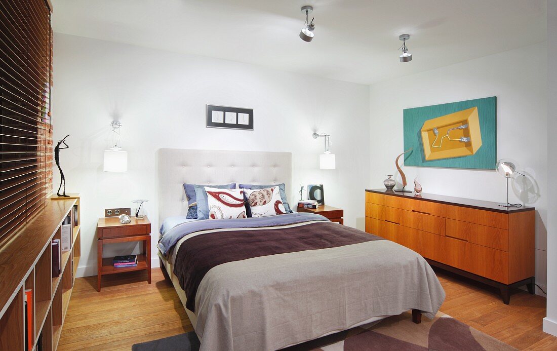 Doppelbett mit gepolstertem Kopfteil neben Sideboard im Fiftiesstil in modernem Schlafzimmer