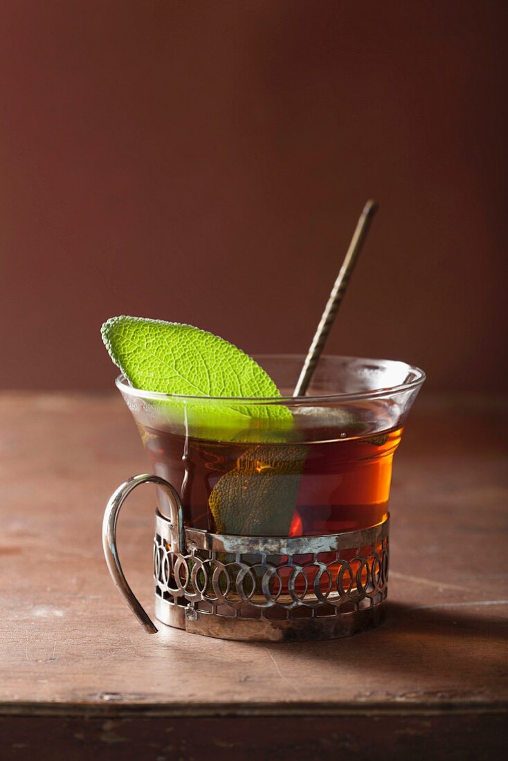 A glass of black tea with a sage leaf