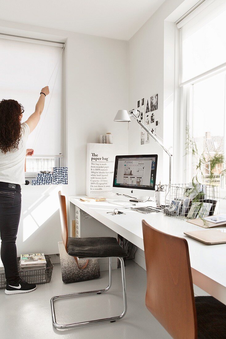 Cantilever chair at white desk, Tolomeo desk lamp and woman stood next to window