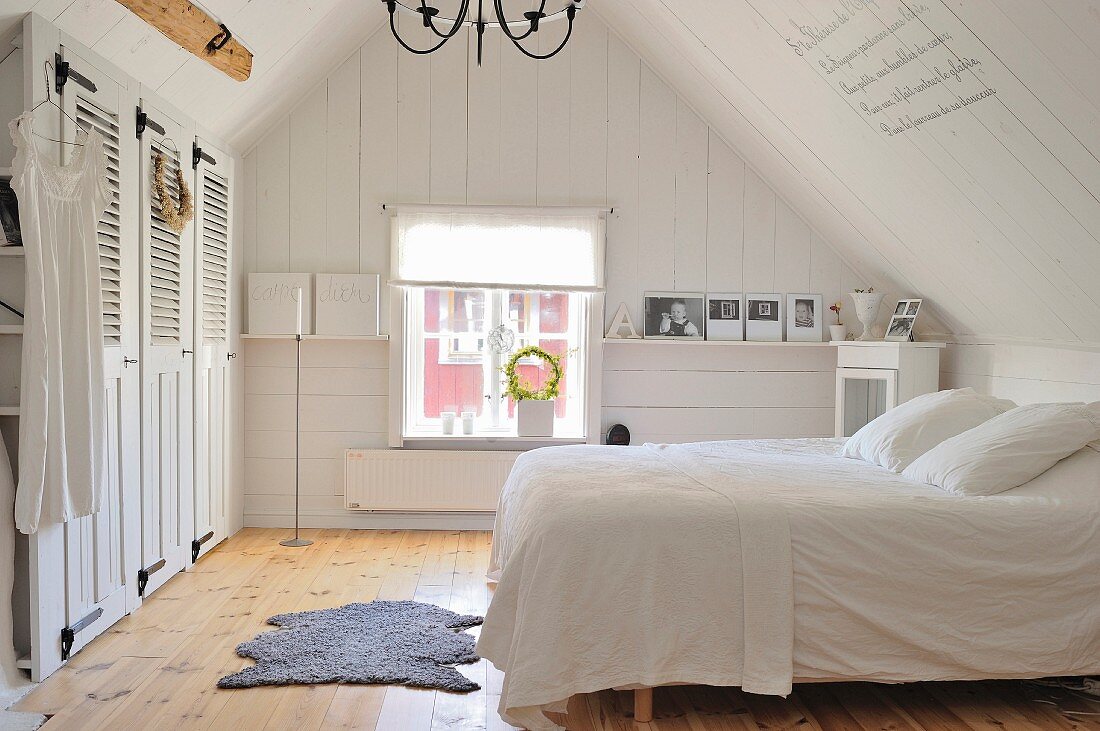 Simple, white, country-house bedroom in attic with fitted wardrobes, plain wooden floor and Scandinavian vintage ambiance