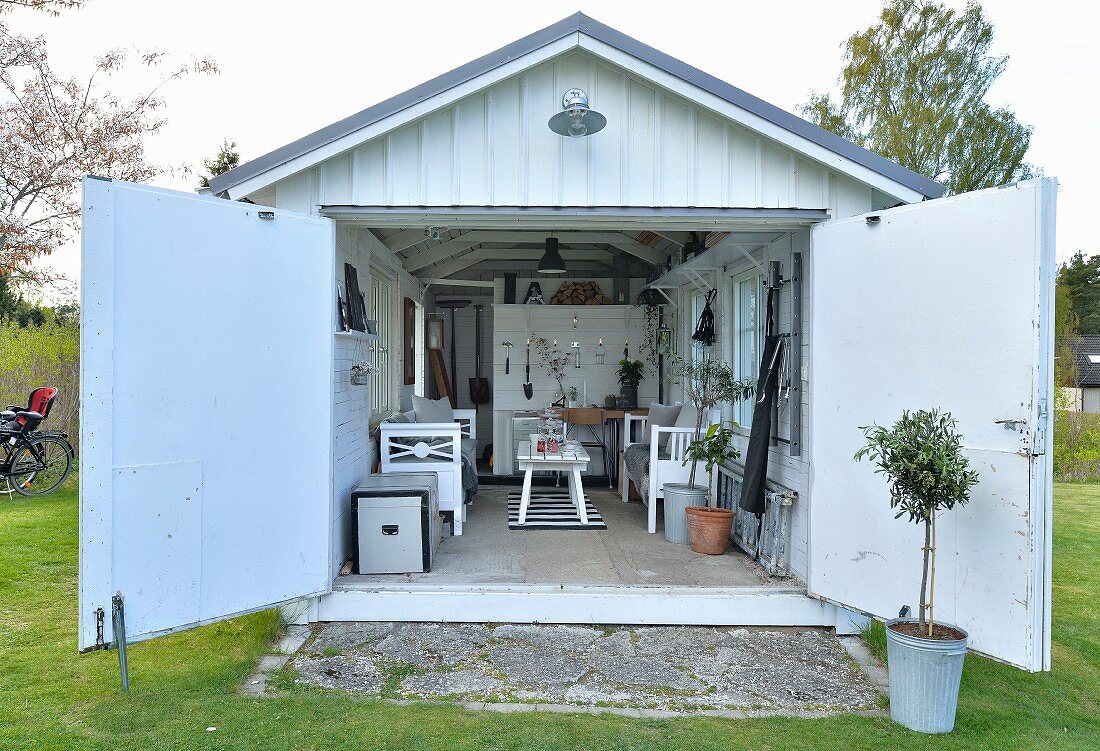 View into converted garage with cosy, vintage furnishings and storage for gardening implements