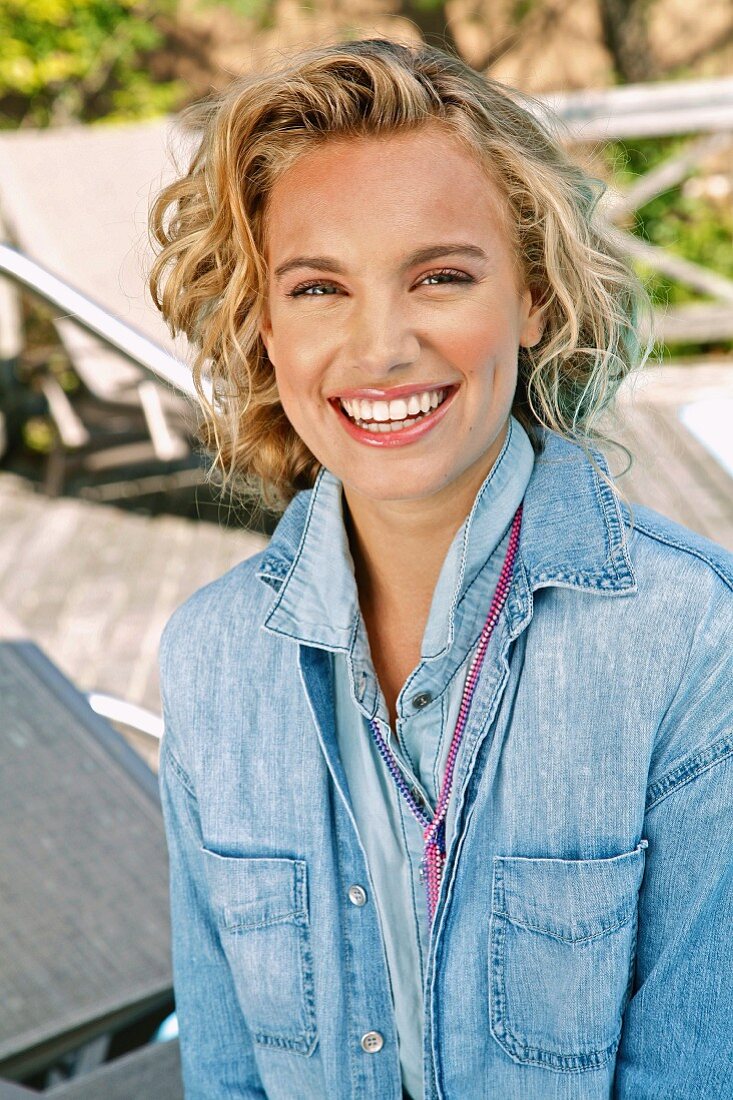 A young blonde woman outside wearing a denim shirt