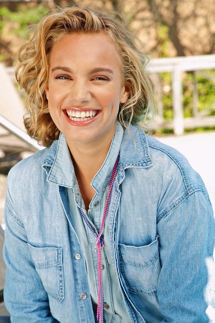 A young blonde woman outside wearing a denim skirt