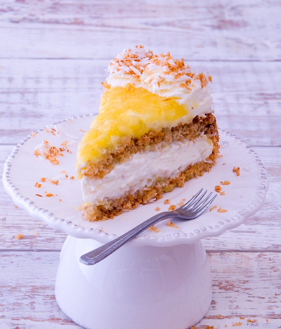 A slice of pineapple cake with cream on a cake stand