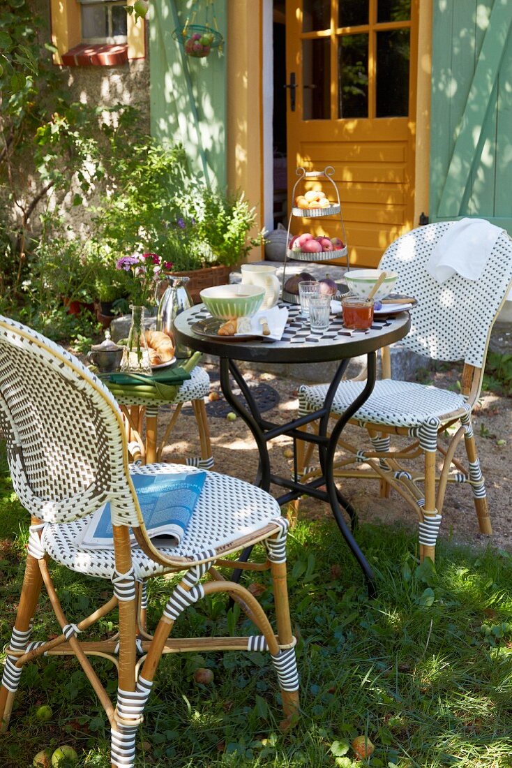 Französisches Frühstück mit Bistromöbeln auf sonnigem Gartenplatz