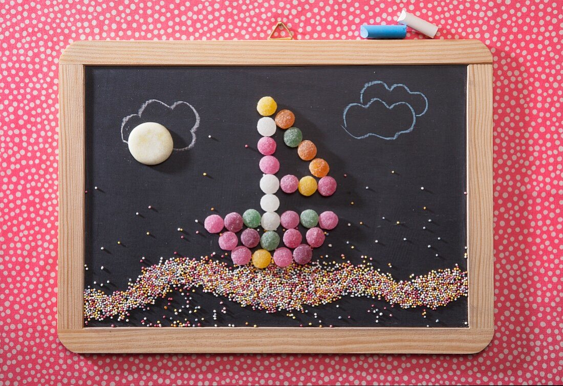 A sailing boat made from bonbons on a chalk board