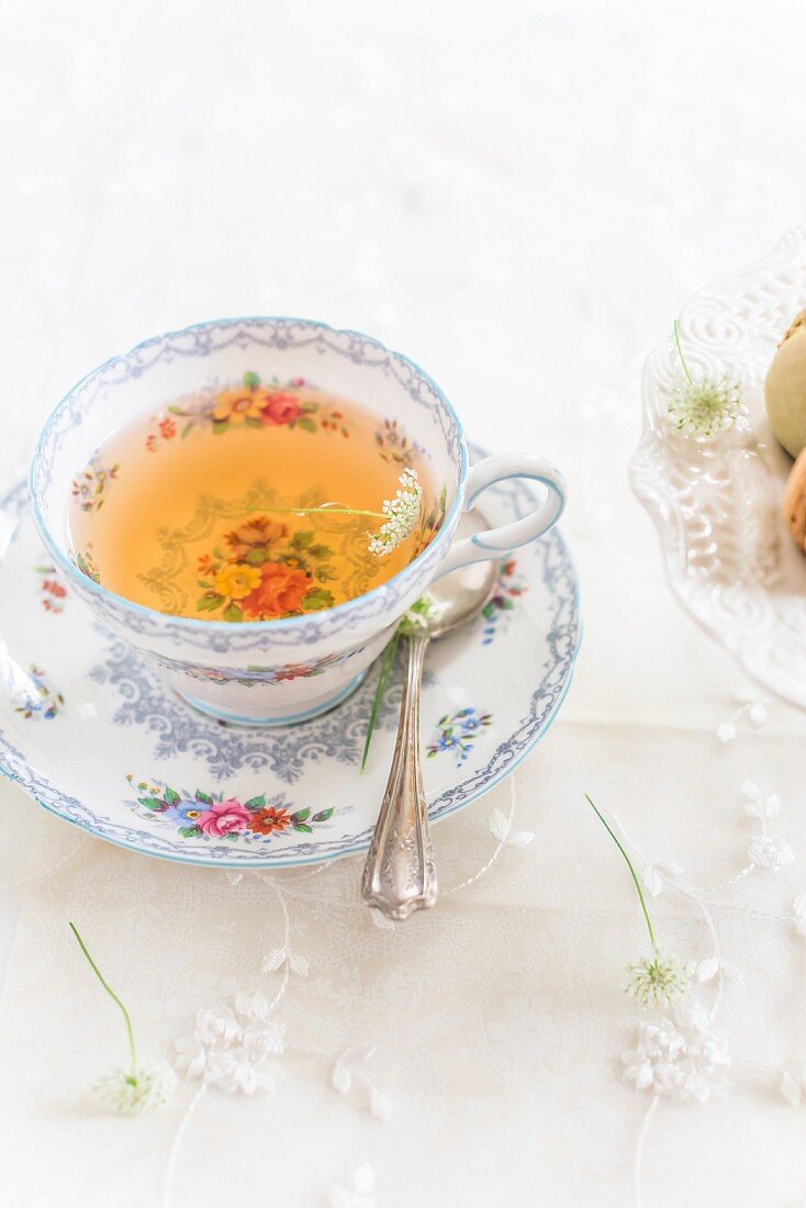 Tea in a floral-patterned cup next to macaroons