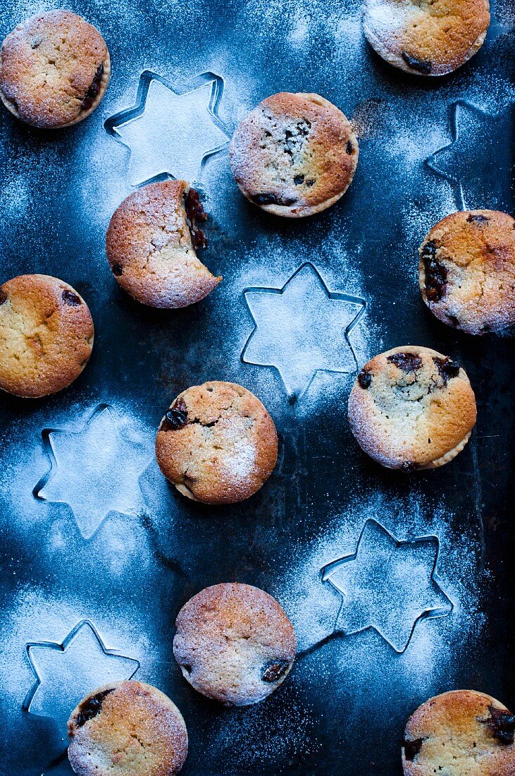 Mehrere Mince Pies mit Puderzucker auf blauem Untergrund mit Sternen