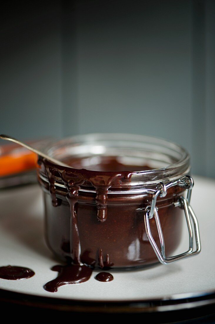An open jar of chocolate fudge sauce on a plate