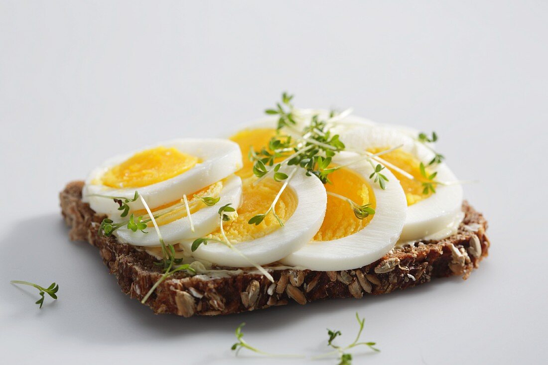 Vollkornbrotscheibe mit hartgekochten Eiern und Kresse